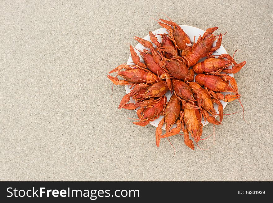 Crayfish on sand, ready to eat in a dish on the shore