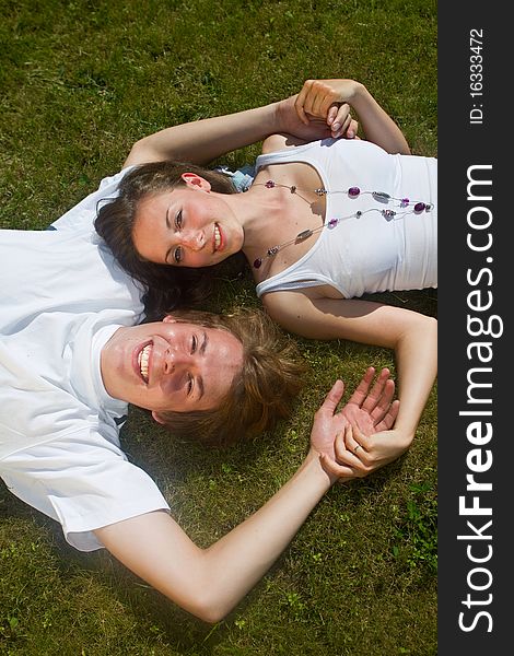 Young couple enjoying a sunny day in the grass. Nice lively image. Young couple enjoying a sunny day in the grass. Nice lively image.