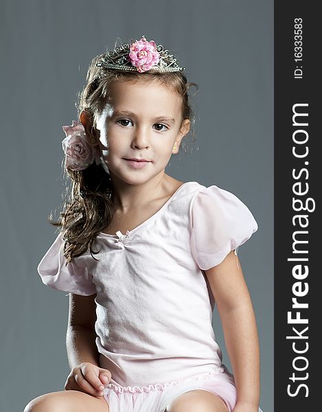 Young cute girl princess against grey background