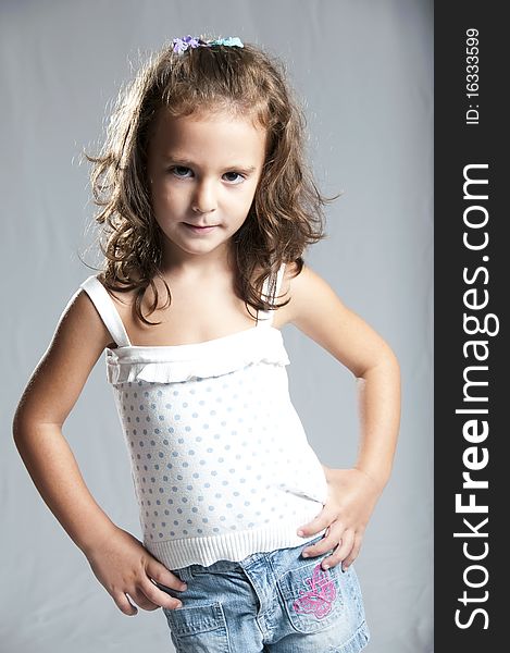 Young cute girl in blue jeans against grey background. Young cute girl in blue jeans against grey background