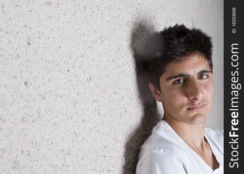 Young teenage boy leaning against a wall in anurban setting. Young teenage boy leaning against a wall in anurban setting.