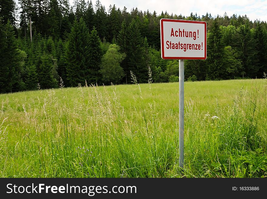 A sign at a border with the writing Achtung Staatsgrenze - attention state frontier