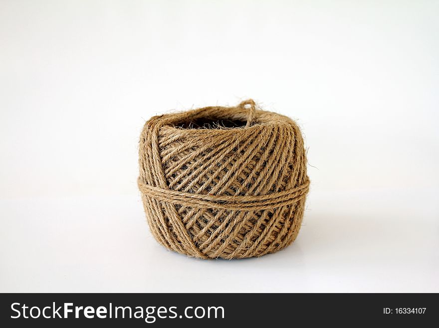 Brown ball of sisal twine; white background. Brown ball of sisal twine; white background.