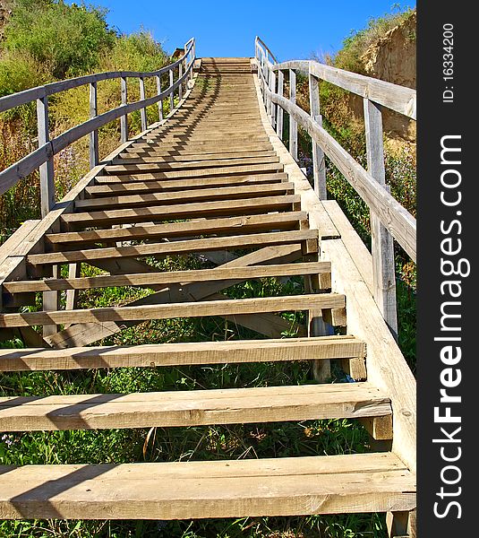 A long wooden staircase rises to the blue sky. Symbol.