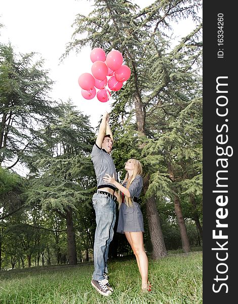 Boy is flying away with balloons, girl is holding him. Boy is flying away with balloons, girl is holding him