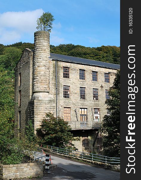 Old textile mill with tree growing out of the chimney in West Yorkshire. Old textile mill with tree growing out of the chimney in West Yorkshire