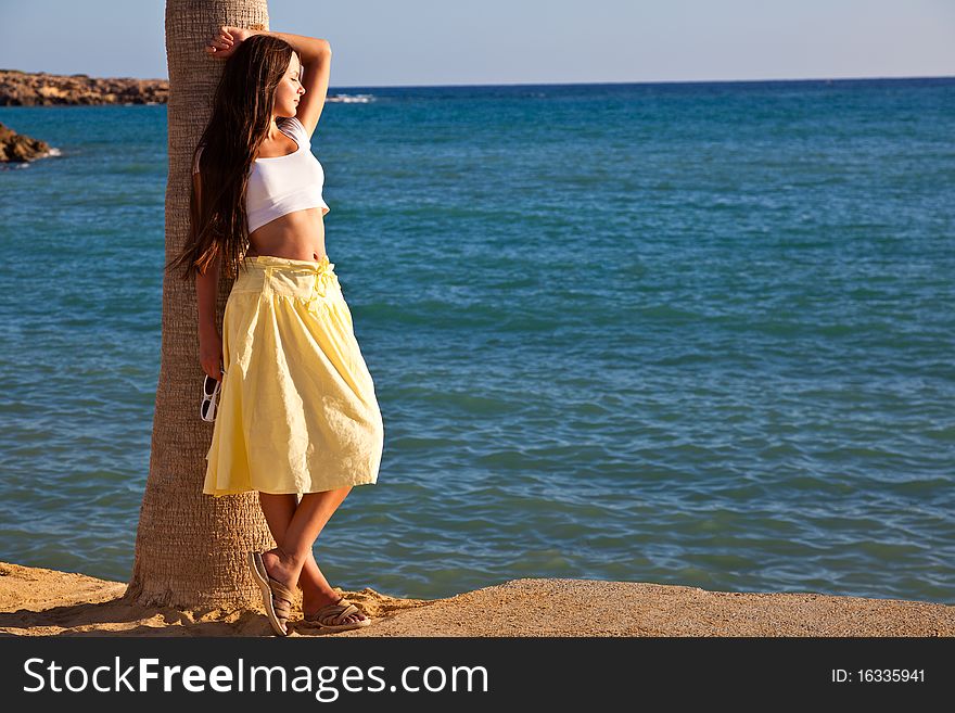 Young woman is standing near the palm tree