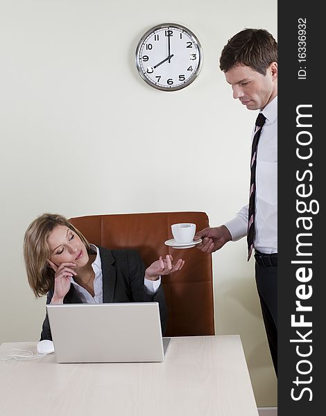 Female manager having coffee served by his male colleague