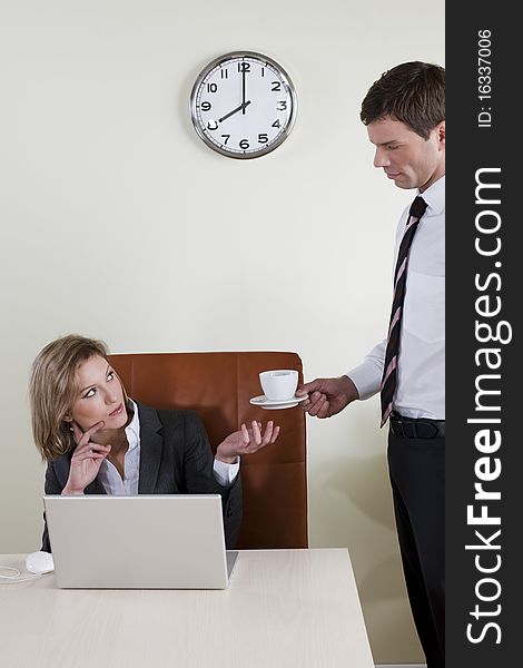 Female manager having coffee served by his male colleague