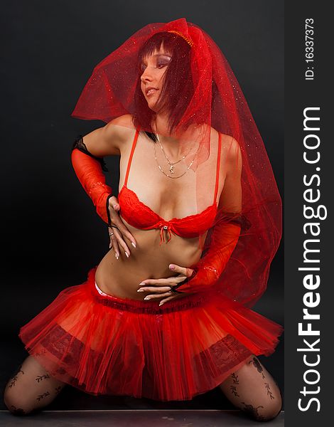 Beautiful dark-haired girl in a red wedding dress isolated on black background in studio. Beautiful dark-haired girl in a red wedding dress isolated on black background in studio