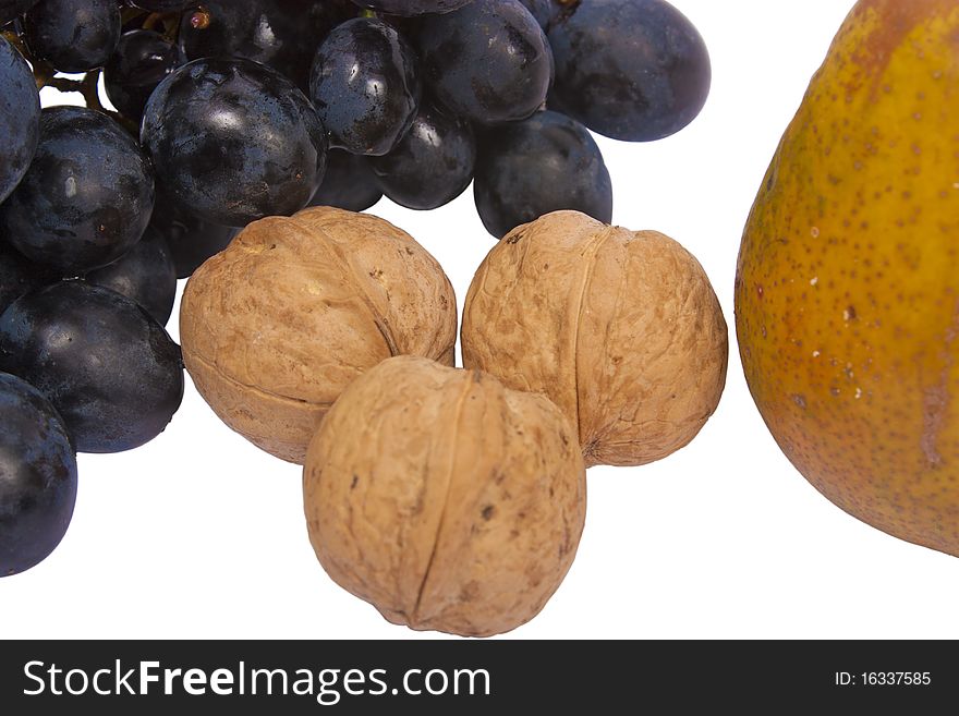 A bunch of grapes, three walnuts and a pear isolated on white background. A bunch of grapes, three walnuts and a pear isolated on white background