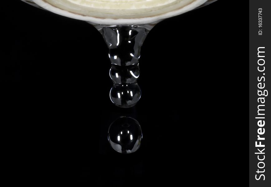 Drops of water coming out of old leaking faucet against black background