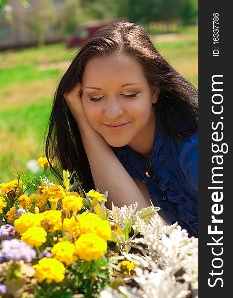 Beautiful girl with long dark hair, in blue shirt with yellow flowers in a sunny park. Beautiful girl with long dark hair, in blue shirt with yellow flowers in a sunny park