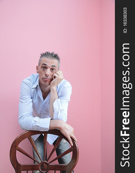 Man with blue shirt leaning on a wooden chair. Man with blue shirt leaning on a wooden chair