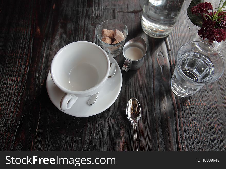 Empty coffee cup next to sugar, cream and a spoon. Empty coffee cup next to sugar, cream and a spoon.