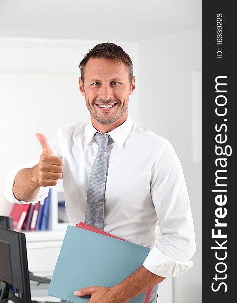 Happy businessman with thumb up in the office. Happy businessman with thumb up in the office