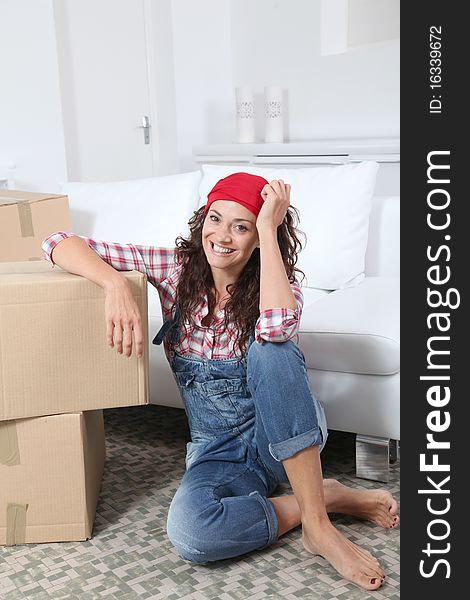 Woman sitting on the floor of living room next to boxes. Woman sitting on the floor of living room next to boxes