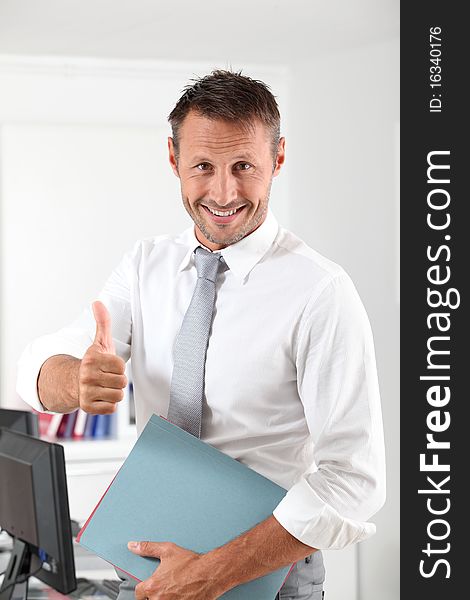 Happy businessman with thumb up in the office. Happy businessman with thumb up in the office