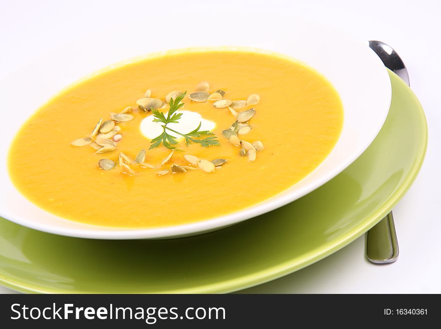 Pumpkin soup decorated with cream, pumpkin seeds and parsley