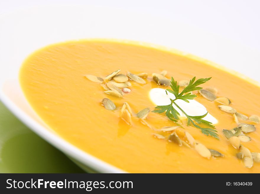 Pumpkin soup decorated with cream, pumpkin seeds and parsley