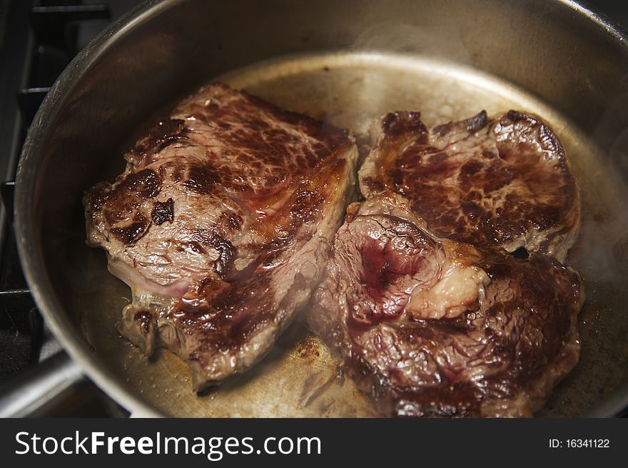 Raw Rib Eyed Steak Frying on a pan