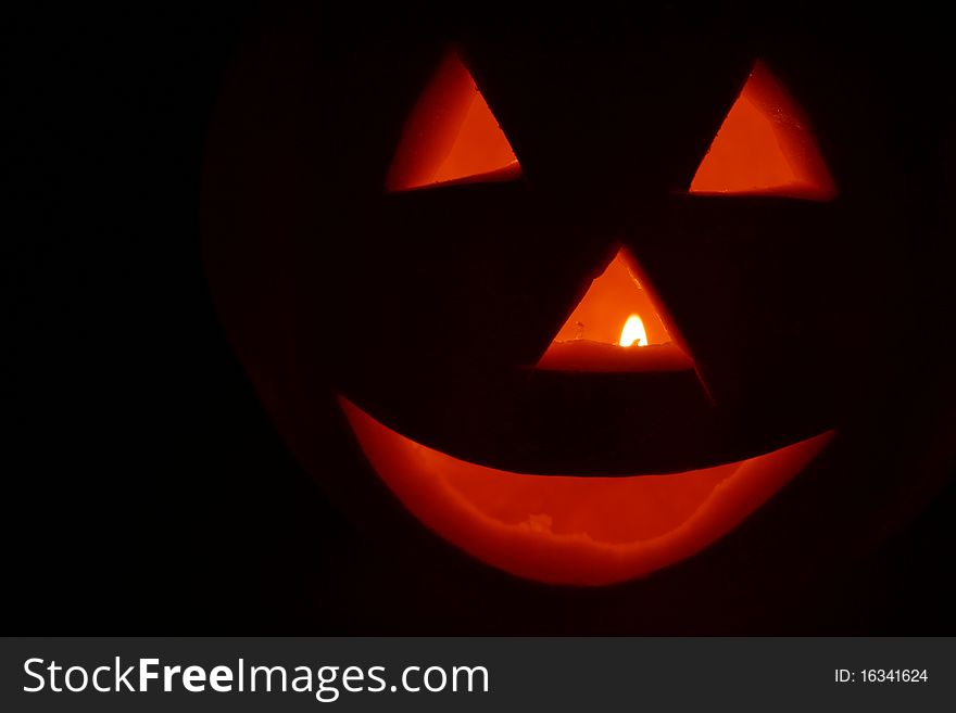 Jack o'lantern glowing on black background with space for text