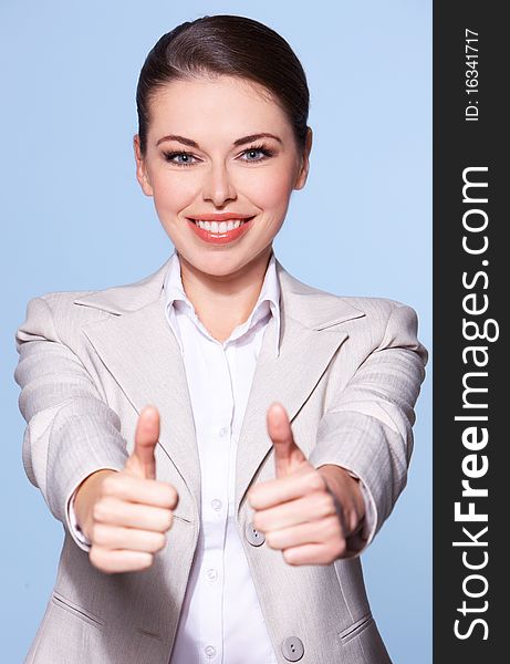 Portrait of beautiful business woman isolated on blue, showing thumbs up