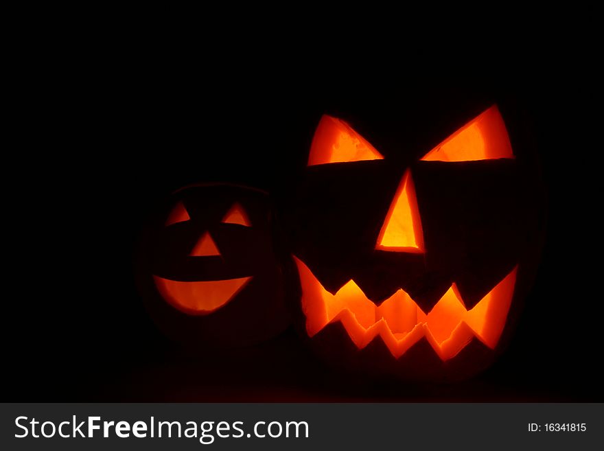 Two Jack-o'-lanterns glowing on black background with space for text