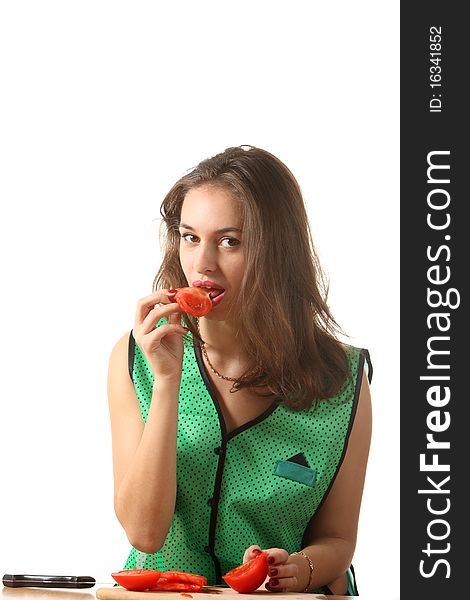 Young girl dressed in green apron eat a peace of tomato. Young girl dressed in green apron eat a peace of tomato