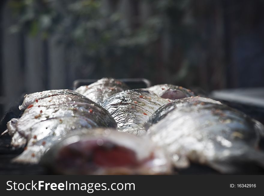 Raw freshwater fish on the grill. Cooked in traditional style. Raw freshwater fish on the grill. Cooked in traditional style