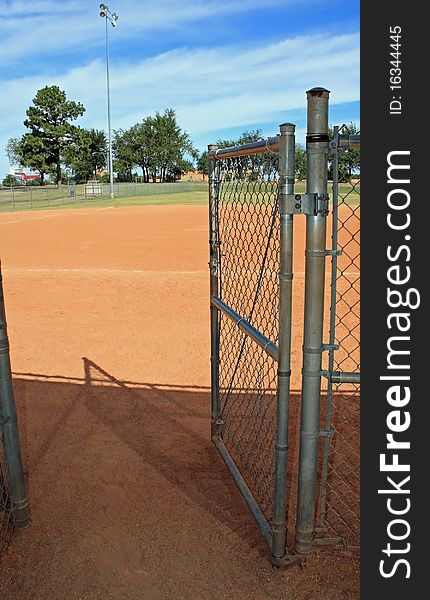 A chain link gate at city baseball park exiting dugout going out. A chain link gate at city baseball park exiting dugout going out.