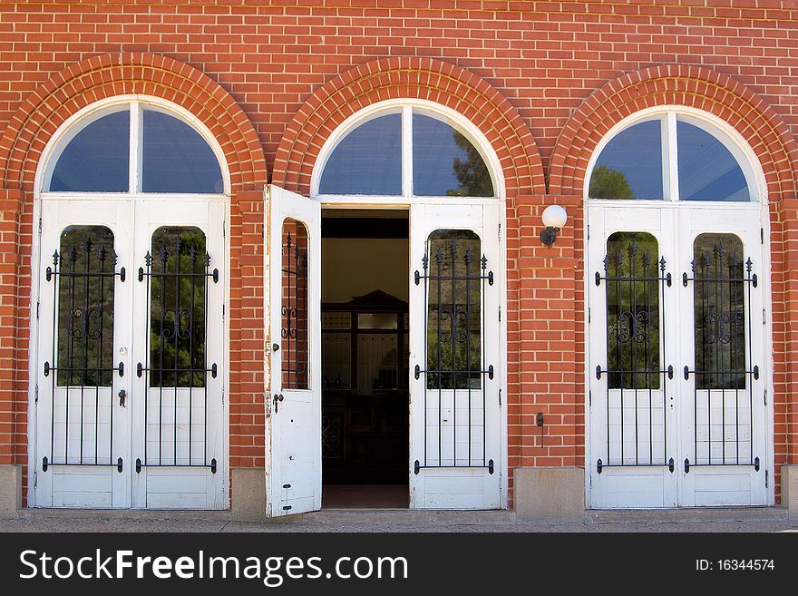 Three doors on an historic brick building, the center door is open.