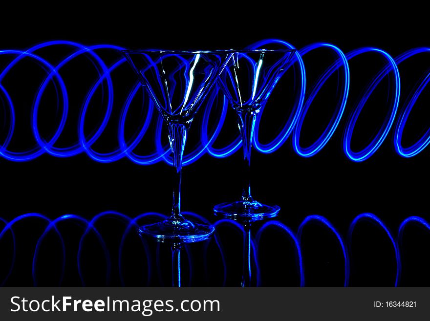 A pair of martini glasses lit with blue led light trails. A pair of martini glasses lit with blue led light trails