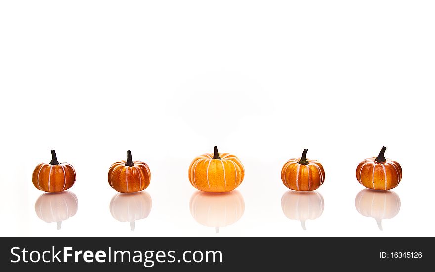 Small pumpkins in a row on a a white background. Small pumpkins in a row on a a white background.