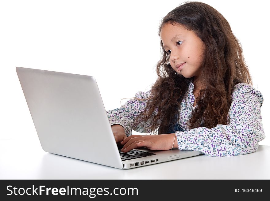 Girl sits before laptop, child with computer against white background