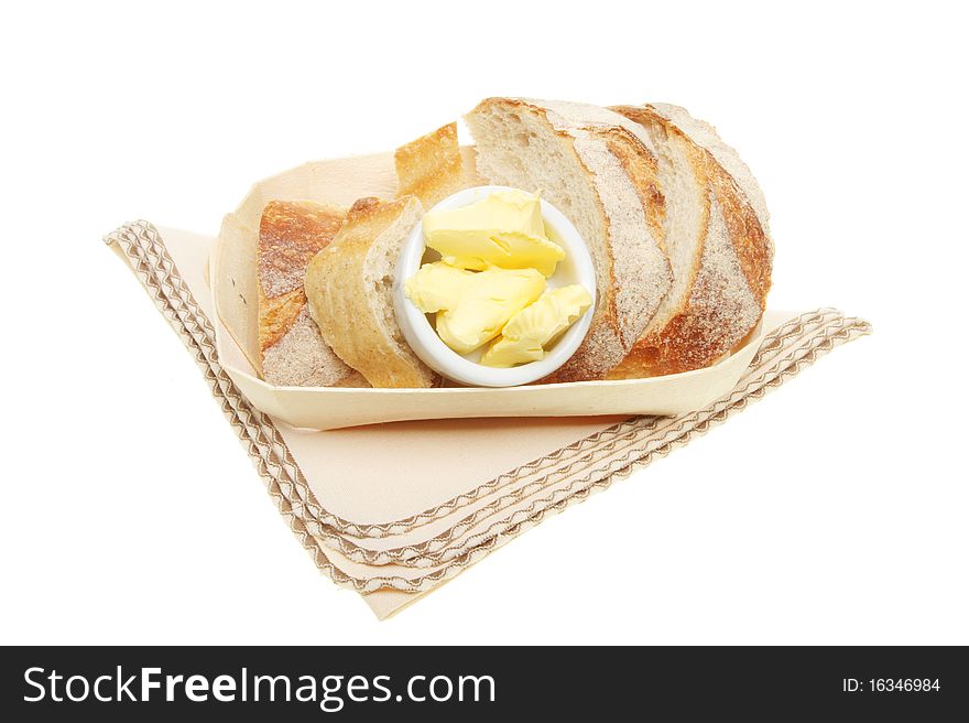 Crusty bread and butter in a basket on a napkin