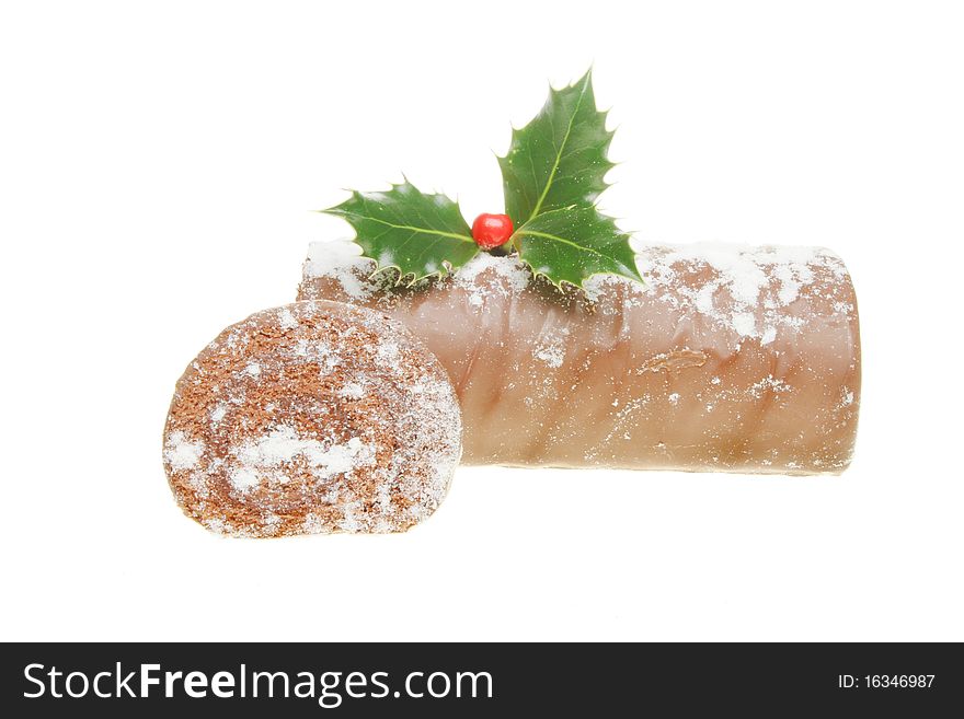 Chocolate yule log dusted with icing sugar and decorated with a sprig of holly