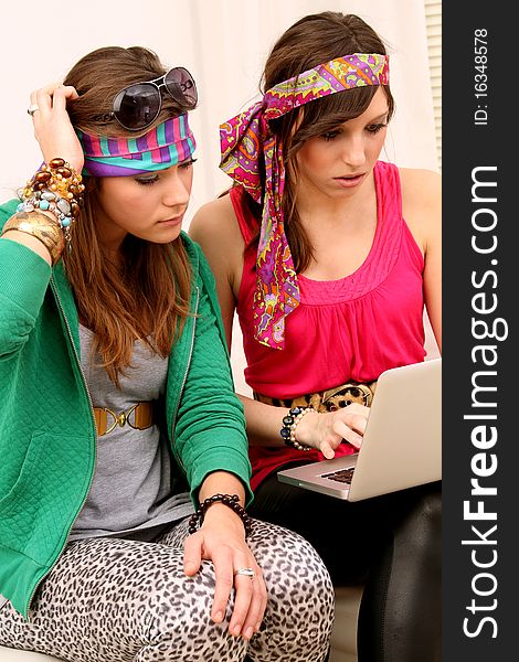 Two girls dressed in hippie style with a laptop. Two girls dressed in hippie style with a laptop