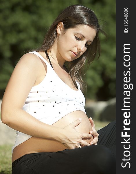 Beautiful pregnant woman relaxing in the park