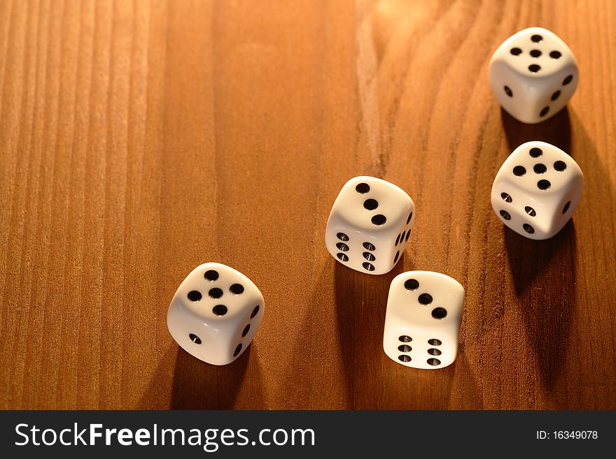 Five white dice lying on wooden background