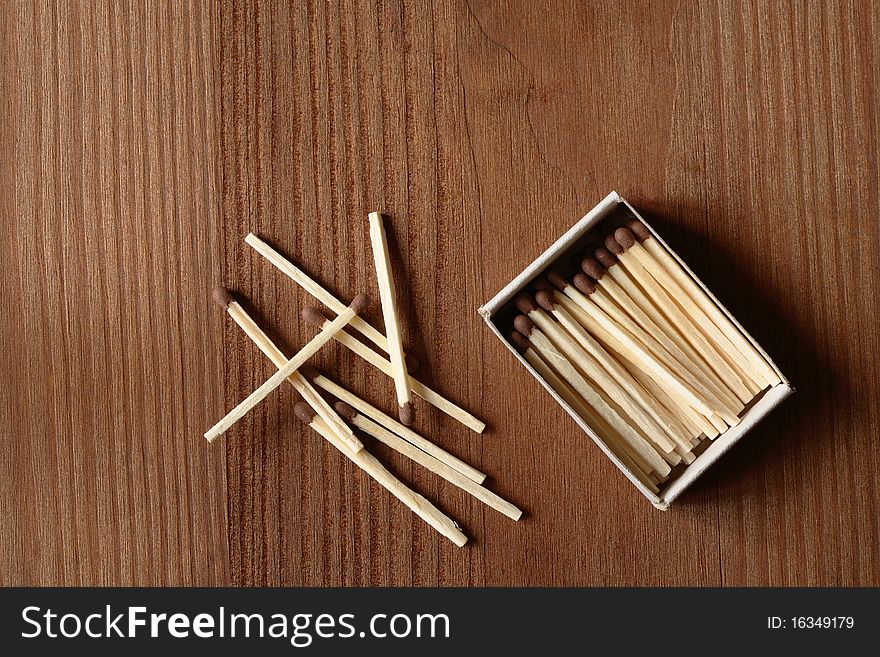 Few matches near matchbox on wooden background