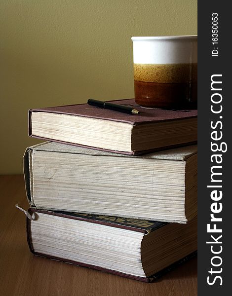 Books pile and coffee cup on wooded table