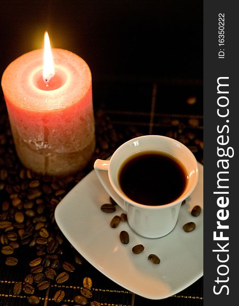 Candle and cup of coffe on the table on the black background. Candle and cup of coffe on the table on the black background.
