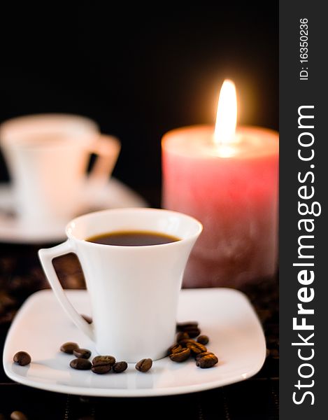 Candle and cups of coffe on the table on the black background. Candle and cups of coffe on the table on the black background.