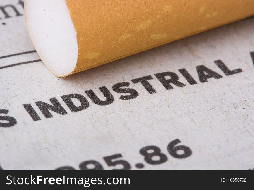 A filtered cigarette laying on a newspaper next to the word industrial.