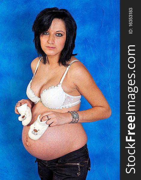 Pregnant woman with children's shoes on the blue mosaic background. Pregnant woman with children's shoes on the blue mosaic background