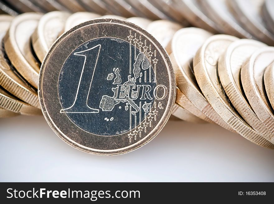 Single Euro leaning against stacks of coins, isolated on white background. Single Euro leaning against stacks of coins, isolated on white background.