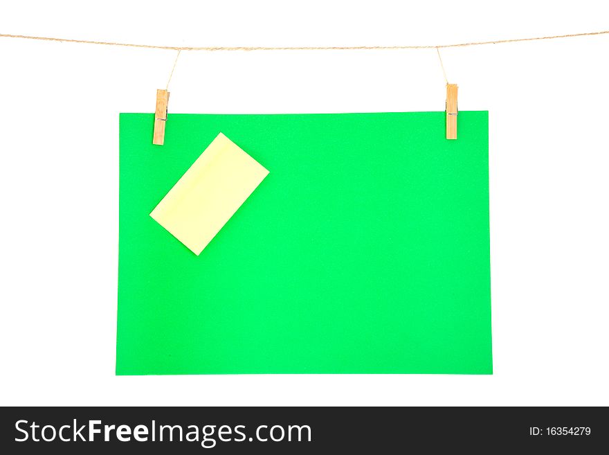 Green paper sheet and yellow on a clothes line. Isolated on white background.