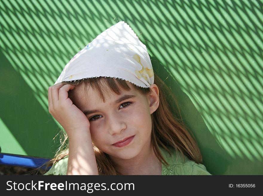 Sad little girl with green background wearing kerchief staring into camera