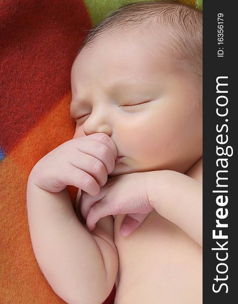 Newborn baby boy lying on a colorful blanket